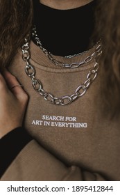 A Closeup Of A Female Wearing A Thick Chain Necklace And A Sweatshirt With Motivational Text 