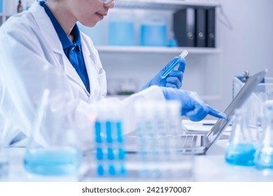 Closeup female woman scientist's hand holding blue liquid chemical chemistry test tube working in analyze science laboratory research experiment - Powered by Shutterstock