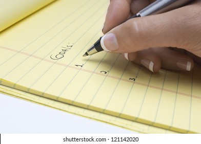 Closeup Of Female's Hand Writing Goals On Notepad