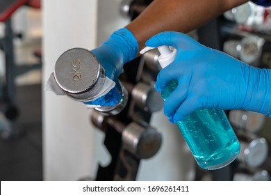 Closeup Female's Hands Using Wet Wipe And Sanitizer Bottle To Clean Dumbbell In Gym.Antiseptic,disinfection,cleanliness And Healthcare, Anti Virus Concept.Anti Bacterial And Corona Virus (COVID-19)