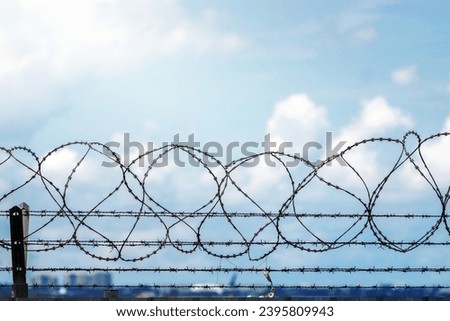 Closeup fence barbed wire with clouds sky background.