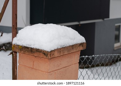 Close-up Of A Fence Post Of Bricks And Mortar At A Chain Link Fence Covered With Snow