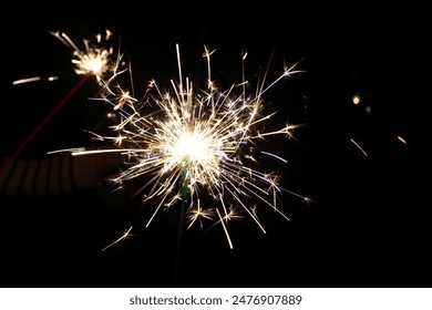 Closeup festive shot friends holding beautiful golden burning sparklers on dark black background - Powered by Shutterstock