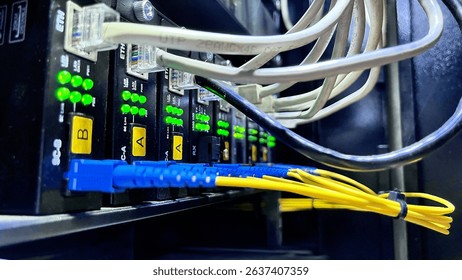 Close-up of fiber optic cables and ethernet ports with active LED indicators in a data center rack.