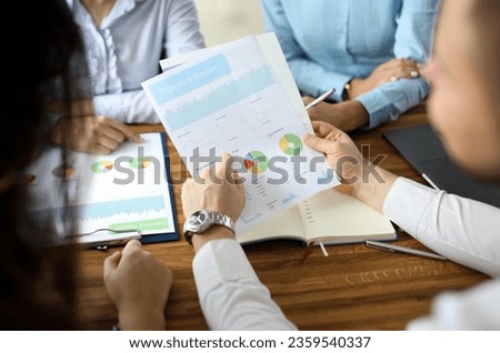 Close-up of financial statement in businessman hands. Biz team speaking about statistics report with graphs, charts, diagram. Business meeting and teamwork concept