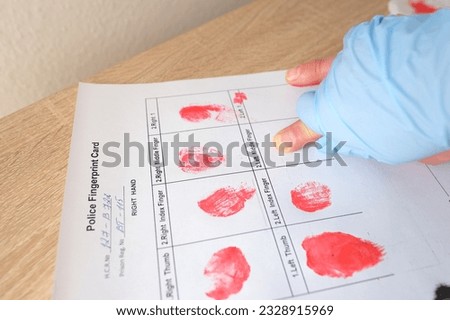 close-up of finger makes fingerprint using special red paint, documents police examination of suspected person, personality identification concept, sweat traces from crime scene, police investigation