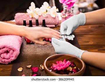 Closeup finger nail care by manicure specialist in beauty salon. 