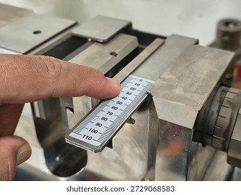 Close-up of a finger pointing at a measuring scale on an industrial testing machine, precision calibration and material strength analysis in a professional laboratory setting