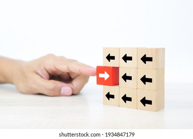 Close-up finger pushing cube wooden toy block stacked with arrow icon pointing to opposite directions for way of adapting to change leader and transform concept.