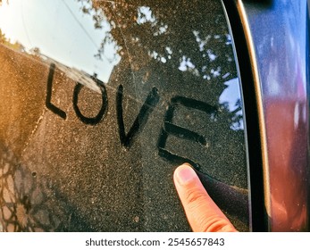 A close-up  of a finger tracing the word "love" in dust on a back window car as symbolizing intimate affection. - Powered by Shutterstock