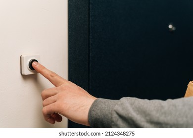 Close-up Finger Of Unrecognizable Man Pushing Doorbell Button In Entryway Of Apartment Building. Closeup Of Male Hand Ringing Door Bell In Block Of Flats. Salesman, Guest Or Visitor Behind Door.