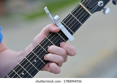 closeup of fingers on the fingerboard of a guitar.