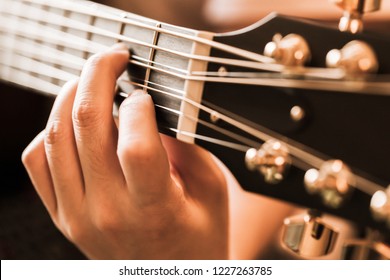 Closeup of fingers from playing 8-string acoustic-electric baritone guitar. Guitar head, steel strings and fingerboard. - Powered by Shutterstock