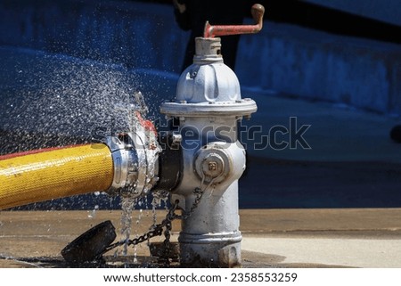 Closeup of a fire hydrant with a large diamiter supply line connected.
