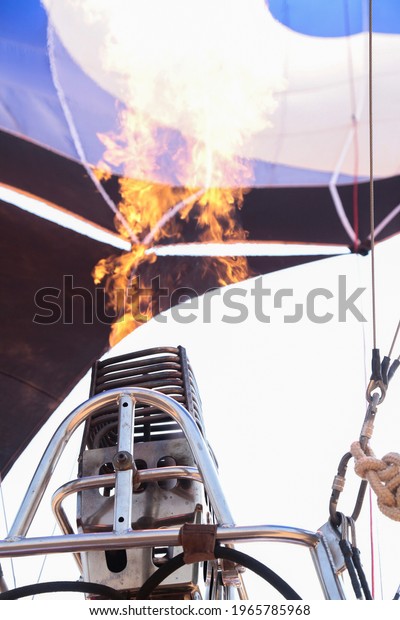 Closeup of the fire to warm the air inside the\
blue, white and black\
balloon.