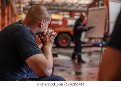 Closeup of firefighter sitting and listening boss who is talking about tactic how they gonna extinguish the fire. Fire brigade interior.