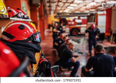 Closeup Of Firefighter Sitting And Listening Boss Who Is Talking About Tactic How They Gonna Extinguish The Fire. Fire Brigade Interior. Closeup Of Protective Suit And Helmet.