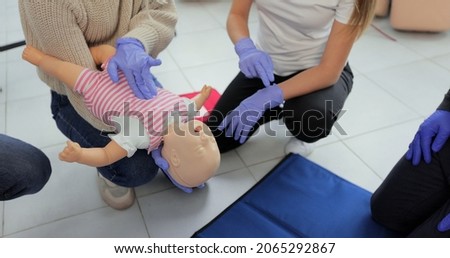 Closeup of first aid instructor using infant dummy demonstrating how to rescue a suffocating baby.