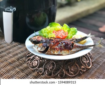 Closeup Fish Grilled With Air Fryer In The White Plate On The Rattan Table.Ready To Eat.Outdoor,balcony,garden.Spicy Food.