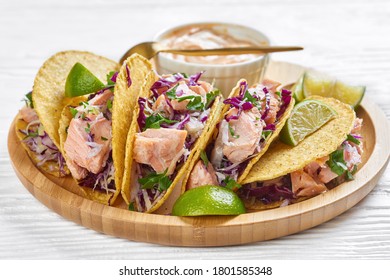 Close-up Of Fish Tacos With Red Cabbage Salad With Spicy Yogurt Sauce Sprinkled With Finely Chopped Parsley Served On A Bamboo Plate On A White Wooden Table, Horizontal View From Above