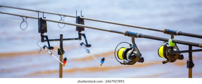 Close-up of fishing rod reels. Fishing on the shore of the lake. Spinning rods for sport fishing. - Powered by Shutterstock