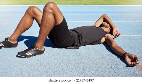 Closeup of a fit active young male athlete lying exhausted flat on the track after a race and feeling tired after a sprint on a running track. Male lacking energy after a hard workout practice run - Powered by Shutterstock