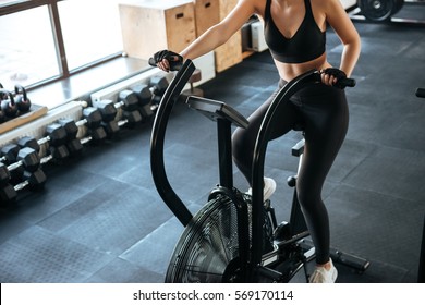 Closeup of fitness woman working out on spinning bicycle in gym - Shutterstock ID 569170114