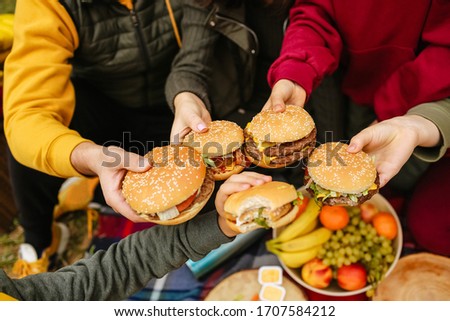 close-up of five burgers in hand, a family on a picnic in autumn and summer, food, delicious, bright colors