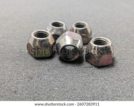 Close-up of Five Lug Nuts on a Textured Surface Showing Threads and Details
