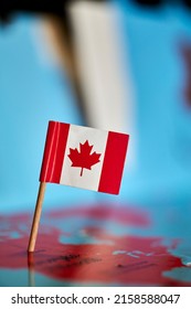 A Closeup Of A Flag Of Canada With A Small Stick On The Map