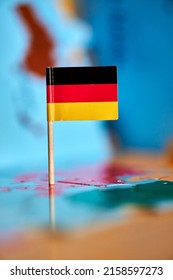 A Closeup Of A Flag Of Germany With A Small Stick On The Map