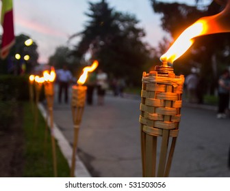 Closeup of flaming torches during an event. Blurred image of people and trees on the background