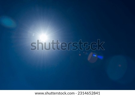 Close-up of flare spots from the sun's rays with the clear blue sky background.