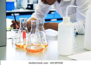 Close-up flasks with liquid solvents equipment in science classroom or chemistry laboratory office with scientist student testing background.