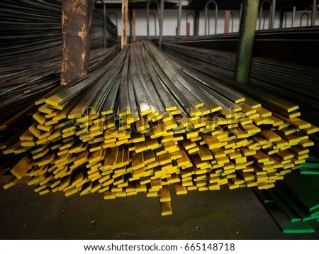 Closeup flat bars stacked on old cement floor,paint yellow color on top ,to be symbol of the thickness,in abstract design,vintage tone,blurry light around.