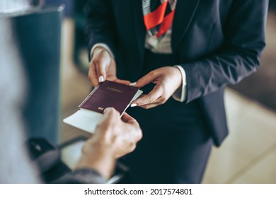 Closeup of flight attendant taking passport of tourist at airport check-in counter. Airport staff checking passport of traveler at airport. - Powered by Shutterstock