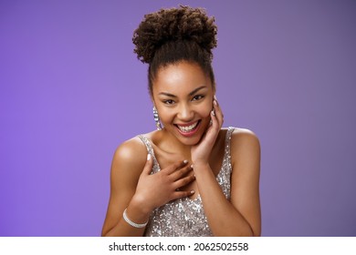 Close-up flirty cheeky young stylish african american woman attend luxurious party in silver dress giggling receive compliment smiling gladly touch chest grateful standing pleased blue background