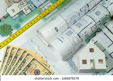 Closeup To Floor Plans, White Paper House, Measuring Yellow Tape And US Dollars. Architect Drawings, Expensive Renovation,  Building Construction Cost, Modern Design, Mortgage Or Credit.  