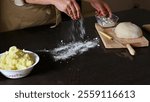 A close-up of flour being sprinkled, dough kneading, and ingredients on a dark wooden kitchen counter for baking.