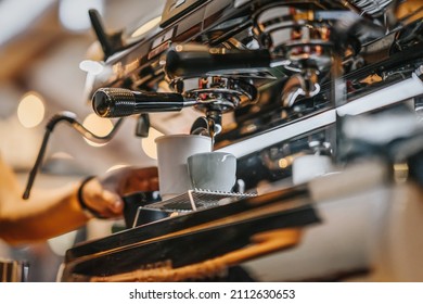 Close-up Of Flowing Coffee From Machine Into Cup. Real Scene In Bar. Coffee Culture And Professional Coffee Making, Service, Catering Concepts