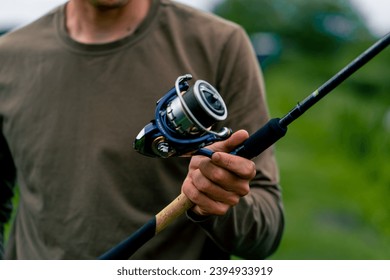 close-up Fly fisherman male hands with fishing rod spinning in hands feeder free style method - Shutterstock ID 2394933919