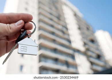 Close-up focus on house key in female hand, against new apartments, cityscape in background. Concept of new home, real estate, and success. - Powered by Shutterstock