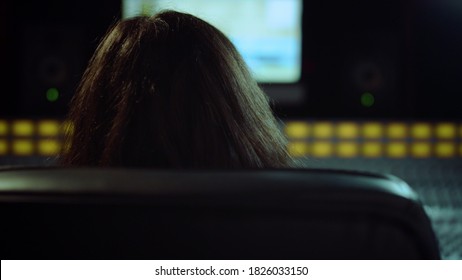 Closeup Focused Sound Engineer Turning On Chair In Music Studio. Portrait Of Male Musician Looking To Camera Indoor. Long Hair Composer Listening Music In Recording Studio.