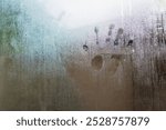 A close-up of a foggy window with a handprint, capturing the essence of human touch against nature.