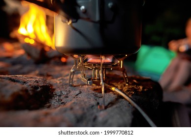 Closeup of foldable camping gas fire system with gas and a pot for fast heating. Adventure lifestyle concept. Selective focus