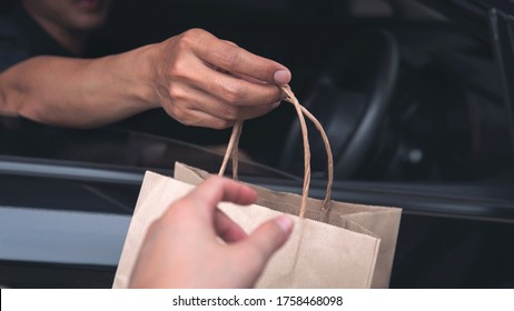 Closeup Food Delivery Man Driver’s Hand Passing Environmentally Friendly Craft Brown Paper Bag To Customer Out Of A Car Window Meeting Social Distancing Requirements And Supporting Small Businesses