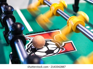 Closeup Of Foosball Table Soccer Game Match Starting, Slow Motion Of Blurry Yellow Player Kicking A Ball With Black Defend Figure. Mini Football Kicker At Indoor Recreation Sport Center.