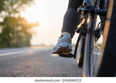 Closeup foot of the bicycle rider on the pedal while riding along the asphalt road in countryside at sunset - Powered by Shutterstock