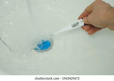 Closeup Footage Of Man's Hand Using Thermometer To Check Water Temperature In Bath. Man Is Preparing A Hot Water To Taking A Bath. He Wants To Relax After Busy Day. Bath For Baby.