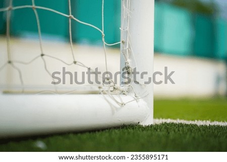 Close-up at football goal post structure which is placed on artificial turf ground pitch. Sport equipment object photo.